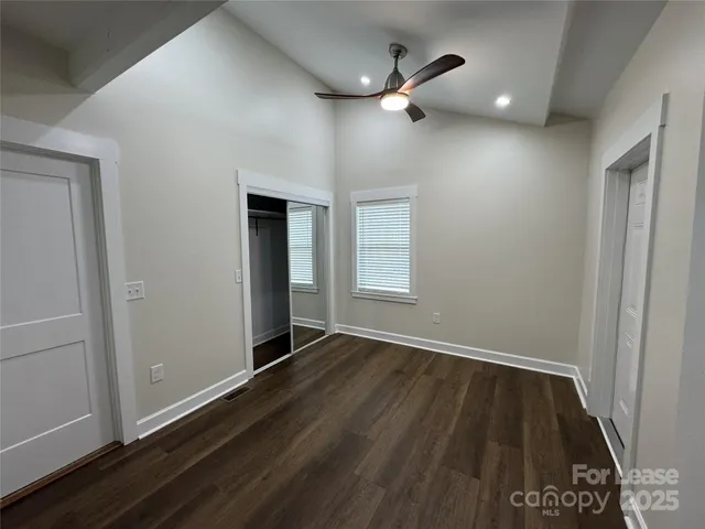 an empty room with wooden floor chandelier fan and windows