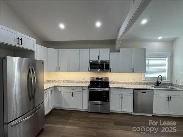 a kitchen with stainless steel appliances granite countertop a refrigerator sink and white cabinets