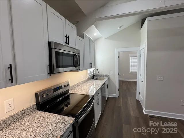 a kitchen with stainless steel appliances a stove a microwave a sink and cabinets
