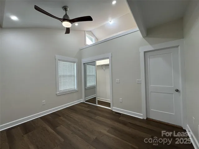 an empty room with wooden floor a ceiling fan and windows