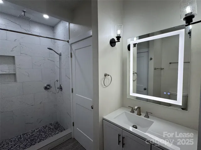a bathroom with a sink shower and a mirror