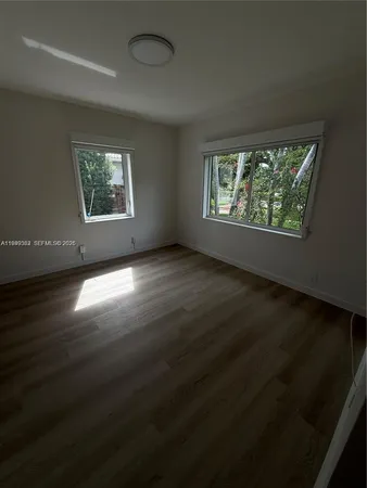 an empty room with wooden floor chandelier and windows