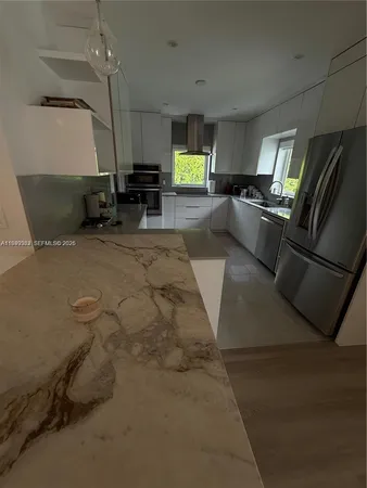 a kitchen with stainless steel appliances kitchen island granite countertop a refrigerator and a stove top oven