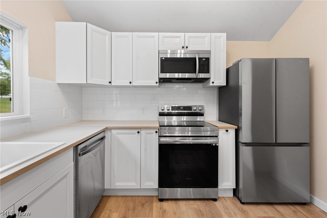 1617 Graham Road Stow, OH 44224 - Photo 22 of 49 Kitchen featuring appliances with stainless steel finishes, light wood-type flooring, backsplash, and white cabinetry