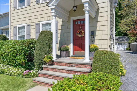 a front view of a house with a yard and plants