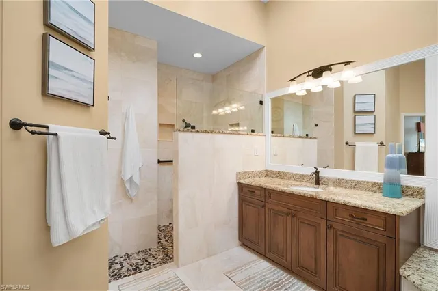 a bathroom with a granite countertop sink mirror and a shower
