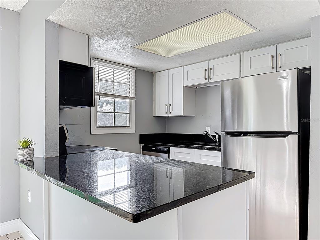 2753 L B McLeod Road, Unit D Orlando, FL 32805 - Photo 15 of 48 a kitchen with stainless steel appliances granite countertop a refrigerator a sink a stove and white cabinets