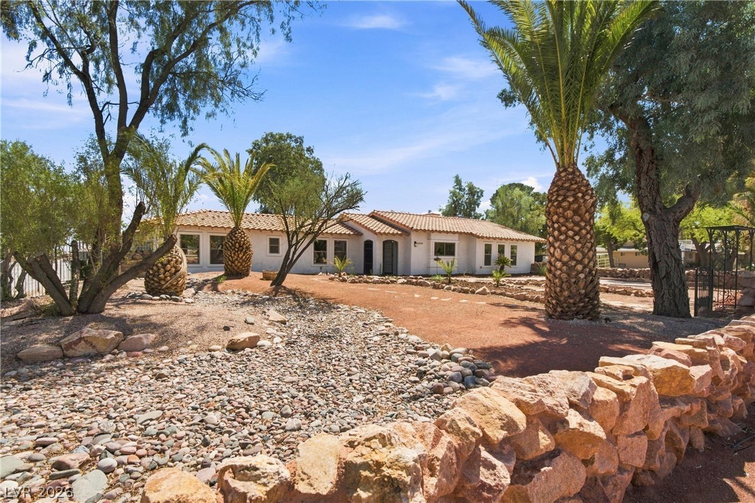 7744 Rancho Destino Road Las Vegas, NV 89123 - Photo 5 of 48 Palm trees and a rustic stone wall frame this single-level Spanish-style residence.