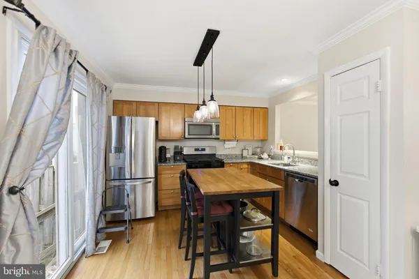 a kitchen with stainless steel appliances granite countertop white refrigerator a stove a dining table and chairs with wooden floor