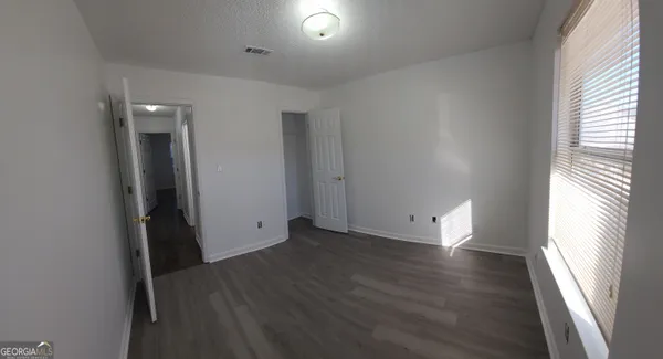 an empty room with wooden floor and windows