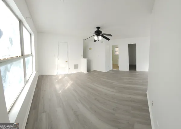 a view of empty room with wooden floor and fan