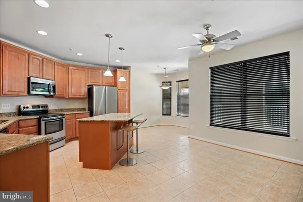 a kitchen with stainless steel appliances granite countertop a refrigerator a stove a sink a microwave and wooden cabinets