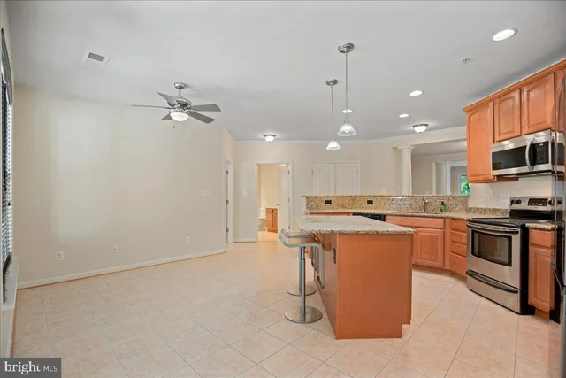 a kitchen with stainless steel appliances kitchen island granite countertop a stove a sink a refrigerator and white cabinets with wooden floor