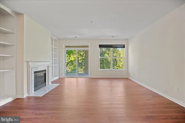 an empty room with wooden floor windows and fireplace
