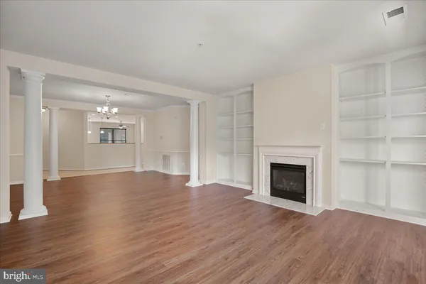 a view of an empty room with wooden floor fireplace and a window