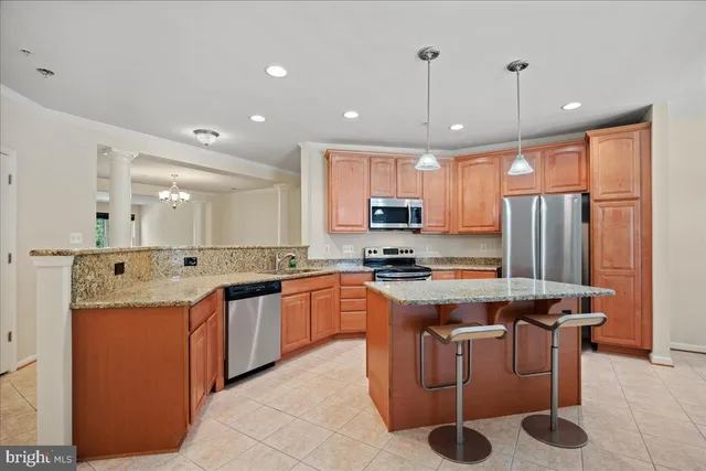 a kitchen with stainless steel appliances granite countertop a sink a stove a refrigerator cabinets and chairs