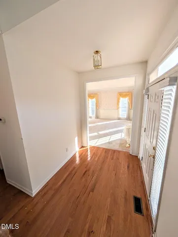 a view of a hallway view with wooden floor and a bathroom