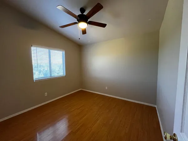 an empty room with a window and a ceiling fan