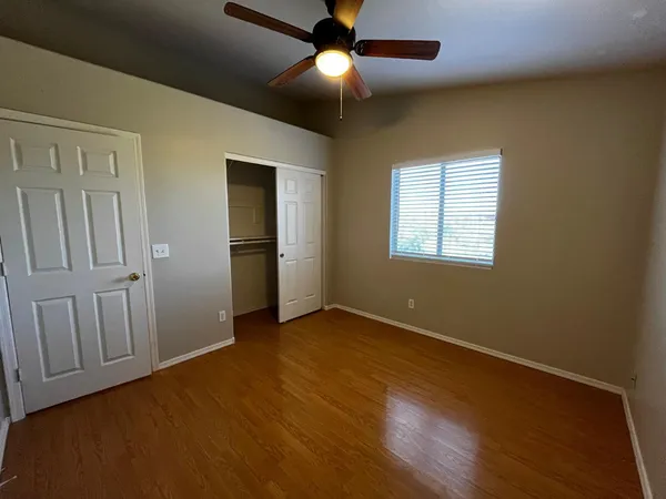 an empty room with wooden floor closet and windows