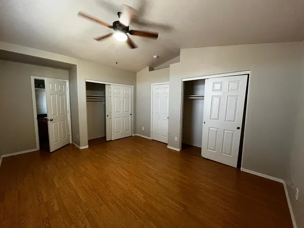 a view of empty room with wooden floor and ceiling fan