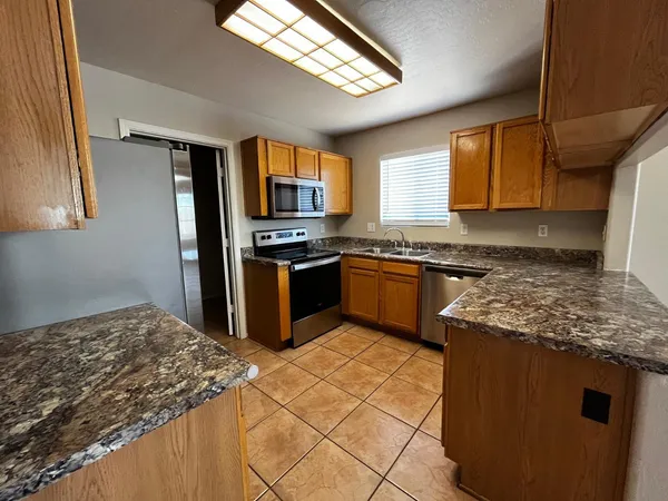 a kitchen with stainless steel appliances granite countertop a stove a sink dishwasher and a refrigerator