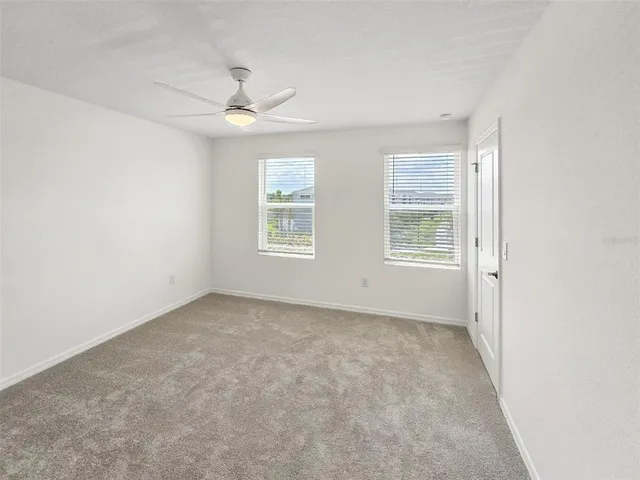 an empty room with windows and ceiling fan