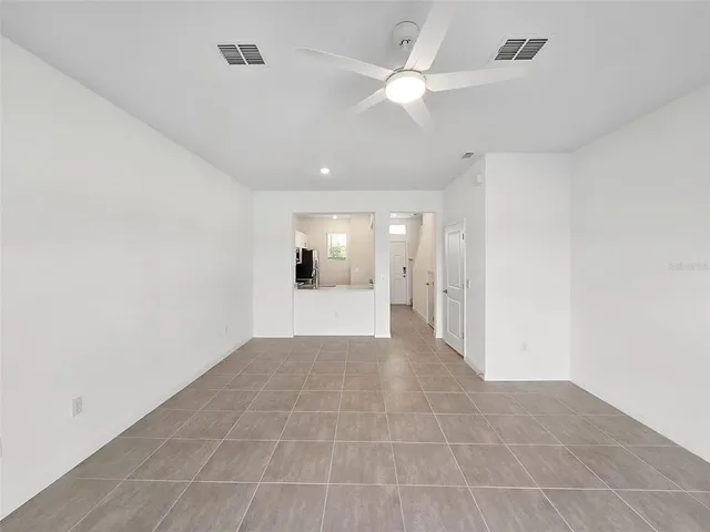 en empty room with a ceiling fan and a rug