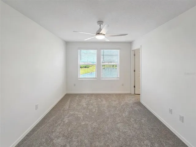 an empty room with windows and chandelier fan