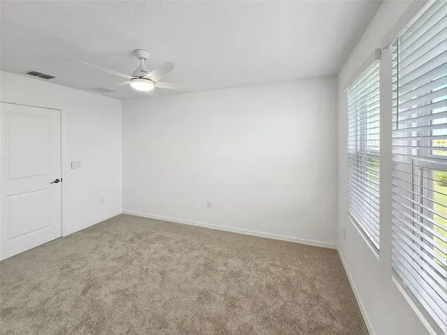an empty room with a window and a fan