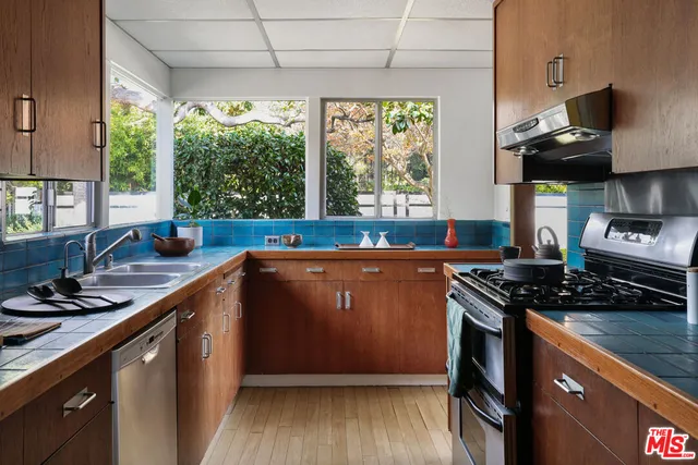 a kitchen with stainless steel appliances granite countertop a sink a stove and a wooden floor