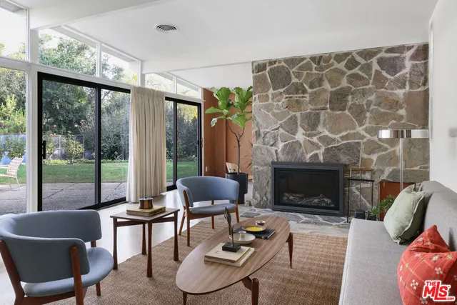 a living room with furniture a fireplace and a floor to ceiling window