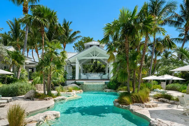 a view of a patio with table and chairs under an umbrella with a large tree