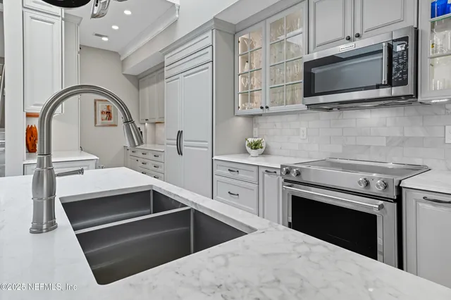 a large kitchen with cabinets chairs and refrigerator