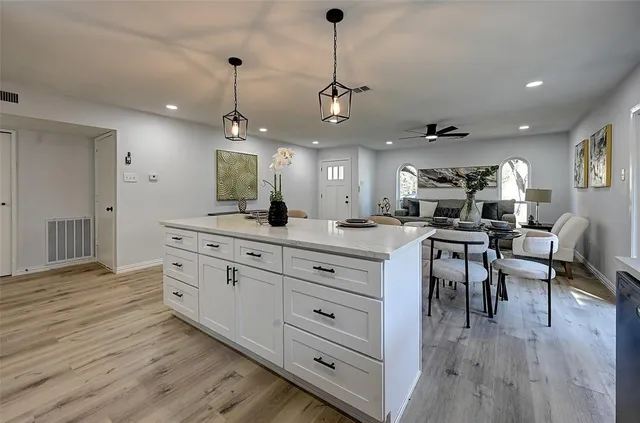 a kitchen with stainless steel appliances granite countertop cabinets a stove a sink a couch and a dining table with wooden floor