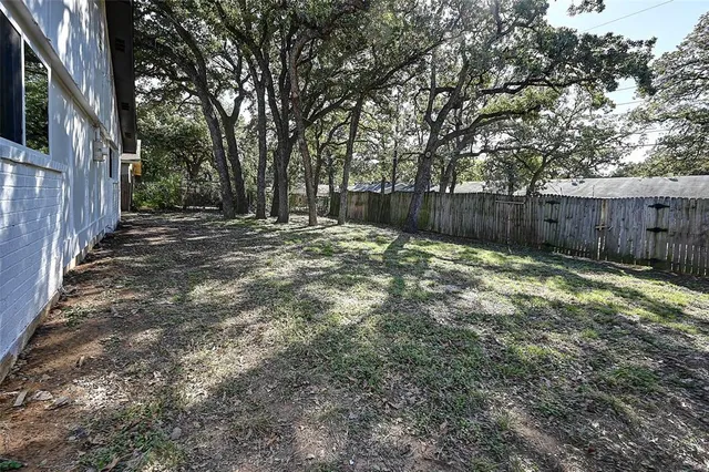 a view of backyard with small cabin and wooden fence