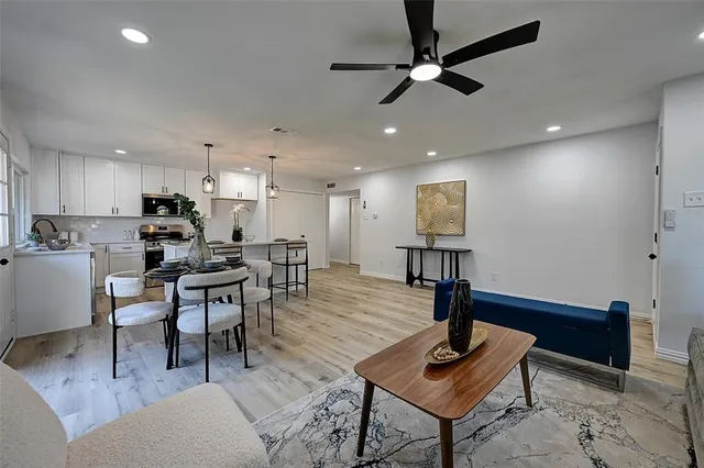 a living room with stainless steel appliances kitchen island a table and chairs