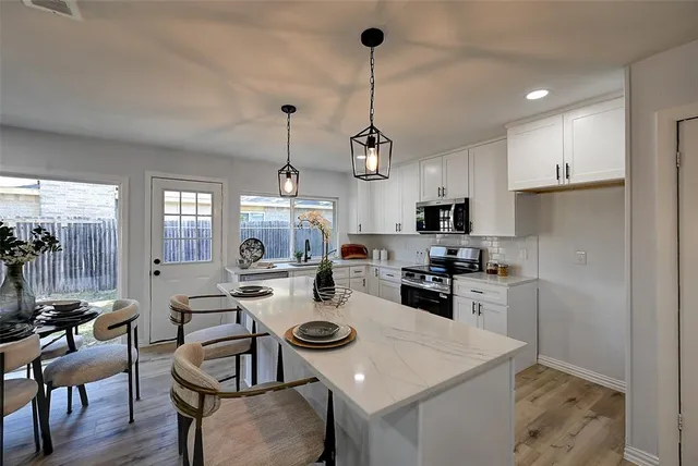 a kitchen with a dining table chairs stove and white cabinets