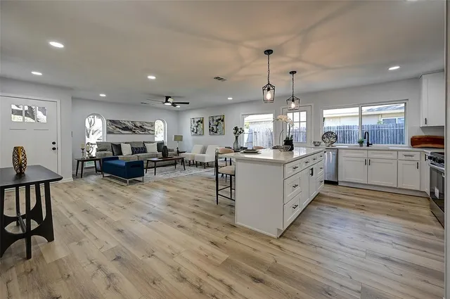 a large white kitchen with lots of counter space and chandelier