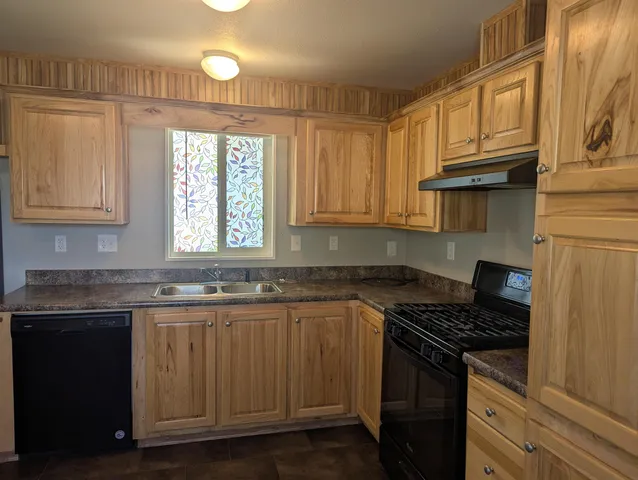 a kitchen with granite countertop a sink stove and cabinets