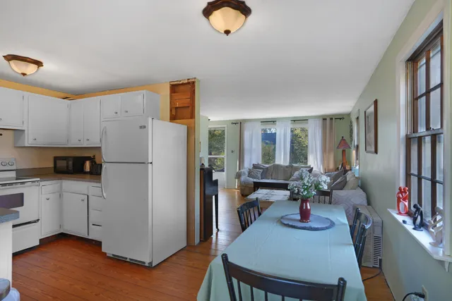 a kitchen with stainless steel appliances granite countertop a refrigerator a stove a sink dishwasher and white cabinets with wooden floor