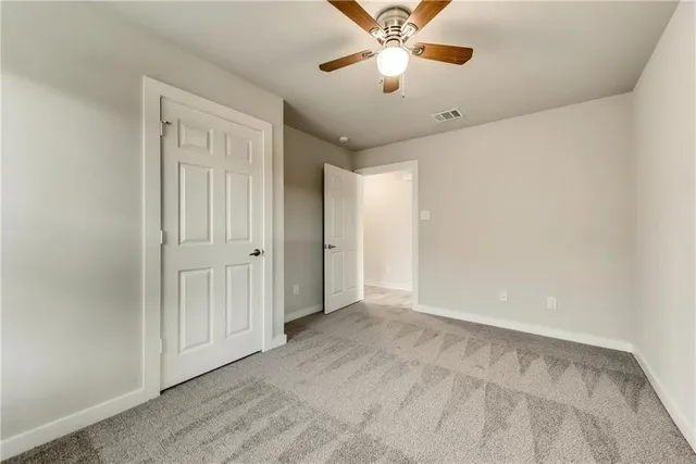 an empty room with a chandelier fan and windows