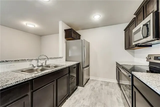 a kitchen with granite countertop stainless steel appliances a sink stove top oven and wooden floor