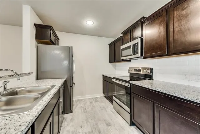 a kitchen with stainless steel appliances granite countertop a sink a stove and microwave