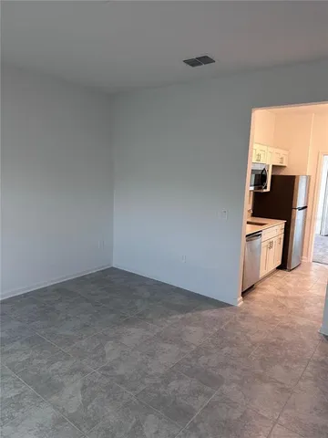 a view of an empty room and a kitchen