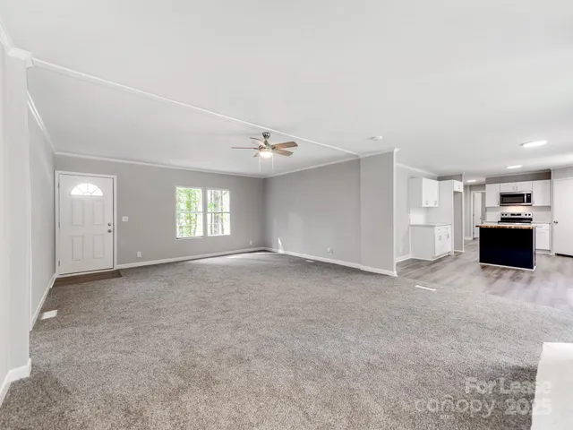 a living room with stainless steel appliances kitchen island granite countertop a stove a sink a refrigerator with grey cabinets and wooden floor