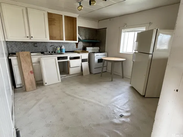 a kitchen with a refrigerator a stove top oven a sink dishwasher and a dining table with wooden cabinet