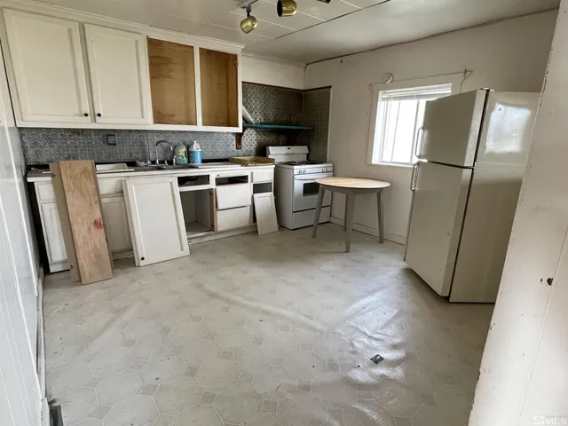 a kitchen with a refrigerator a stove top oven a sink dishwasher and a dining table with wooden cabinet