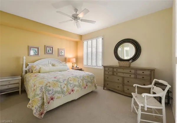 a spacious bedroom with a bed a chandelier and a dresser