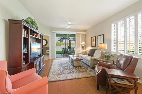 a living room with furniture a flat screen tv and large windows