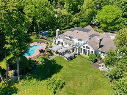 an aerial view of residential houses with outdoor space and trees all around
